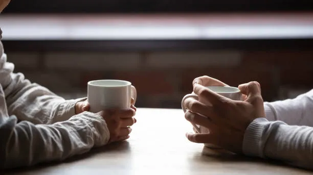 de-cerca-mujer-y-hombre-sosteniendo-tazas-de-café-en-la-mesa